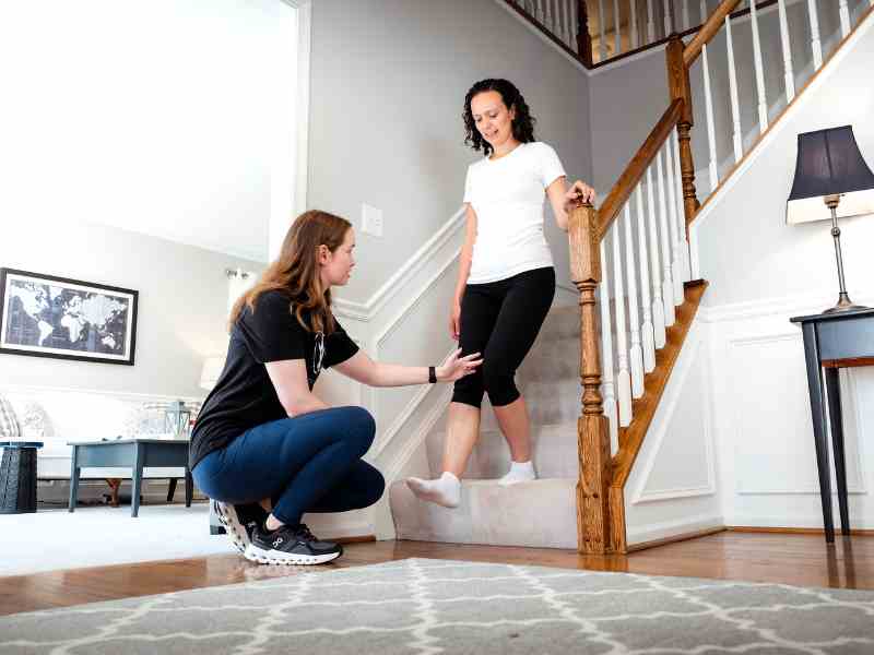 MovementX provider Morgan Groover, PT, DPT helping a patient test her ankle mobility on a treatment table in-home.