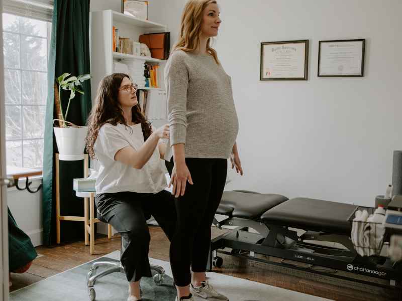 MovementX provider McKenzie Van Loo helping a pregnant woman during a physical therapy session at home.