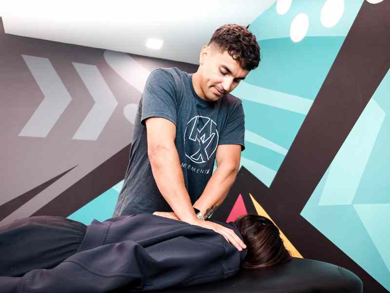 MovementX provider Cesar Laboy, PT, DPT doing a manual manipulation on a patient's thoracic spine, on a treatment table.