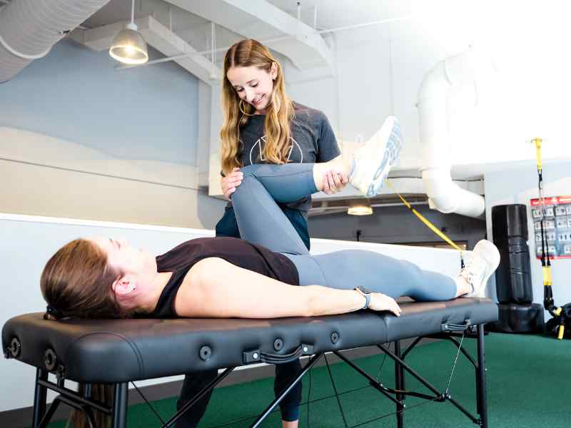 A MovementX provider helping a patient mobilize her hip joint using manual therapy techniques.