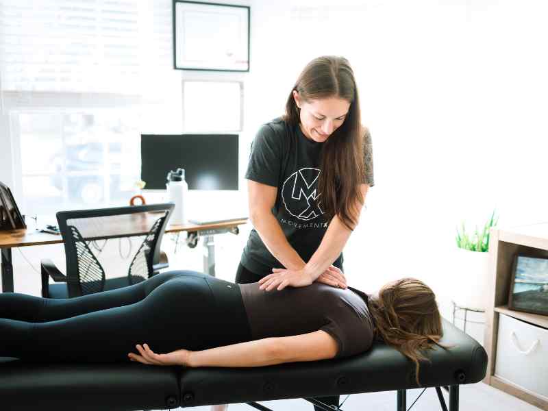 A MovementX provider helping a patient reduce inflexibility in her upper back using manual therapy.