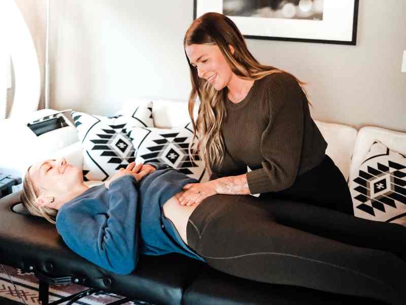 Morgan Knapp, doctor of physical therapy helping a patient in Bend, Oregon in home work through abdominal mobility movements.