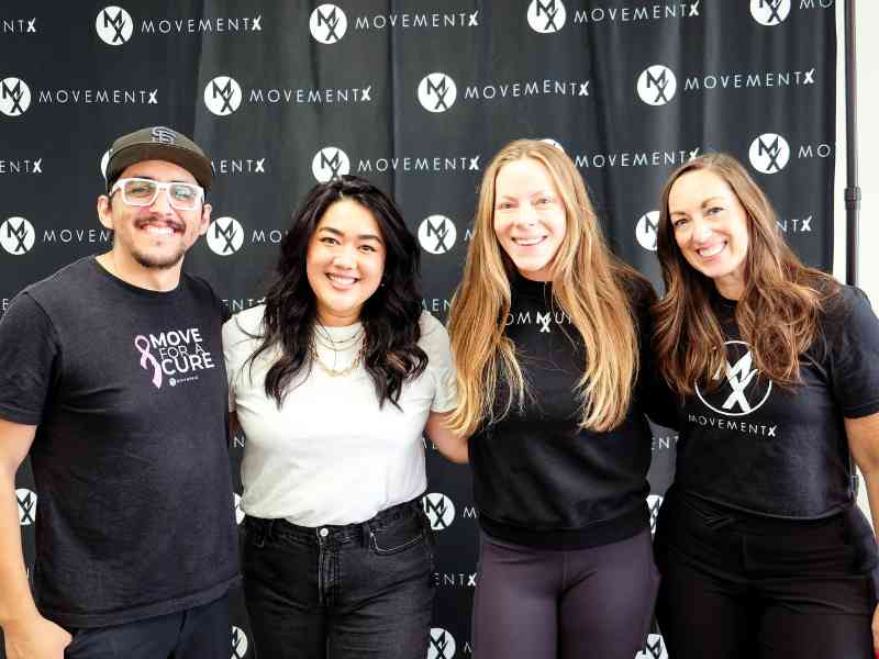 Rich Ortiz, PT, DPT standing arm in arm with 3 other MovementX team members in front of a branded backdrop at a community event in Washington D.C.