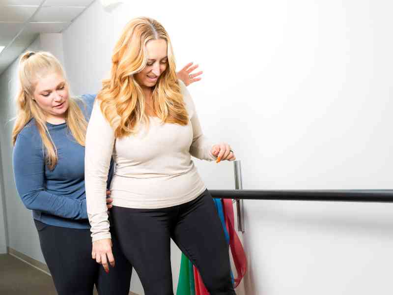 Mattie Overton, PT, DPT helping a patient do a balance exercise during a treatment session.