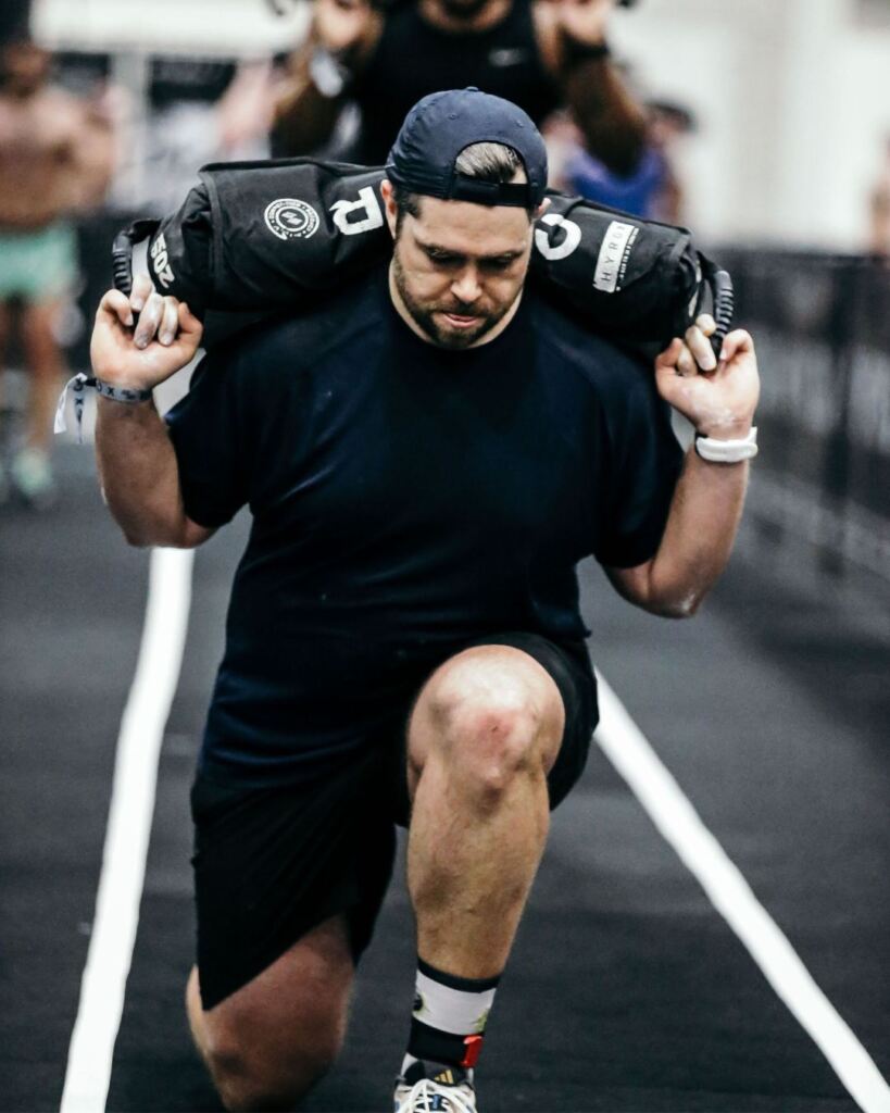 James Cousler, PT, DPT doing a sandback back lunge during a HYROX race.