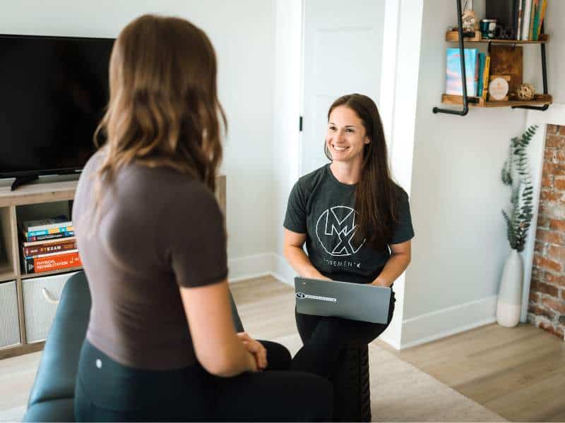 MovementX provider Jillian Chiappisi, PT, DPT analyzing a patient's forearem tension during an in-home physical therapy session.