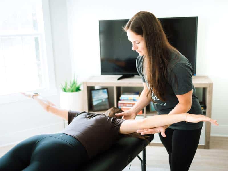MovementX provider Jillian Chiappisi, PT, DPT analyzing a patient's forearem tension during an in-home physical therapy session.