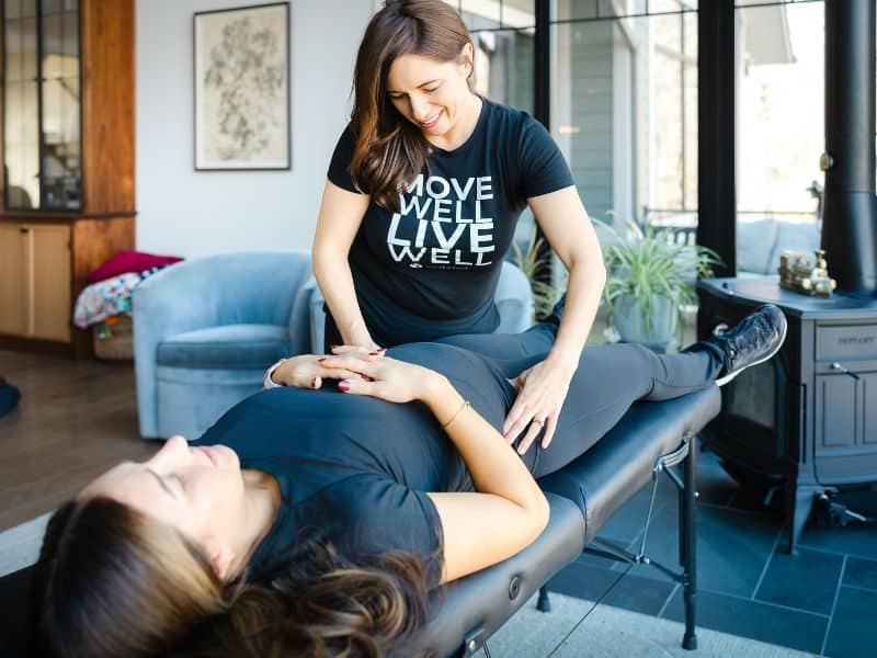 MovementX provider Kaylene Hernandez helping a postpartum patient on a treatment table in-home during a session