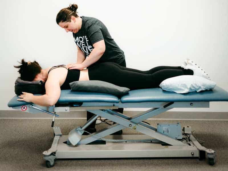 MovementX Provider Katelyn Nicoletta, PT, DPT helping a patient address shoulder pain on a treatment table during a session.