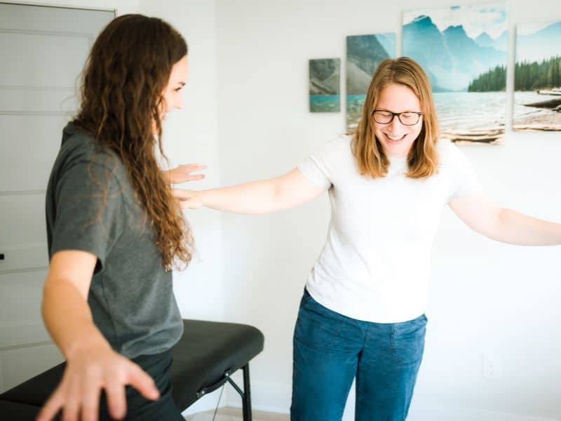 A MovementX provider helping a patient perform a balance activity in home to test balancing capacity on one leg.