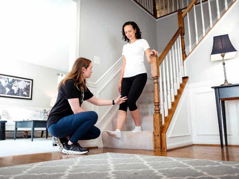 MovementX provider Morgan Groover, PT, DPT helping a patient do a staircase balance exercise in home.