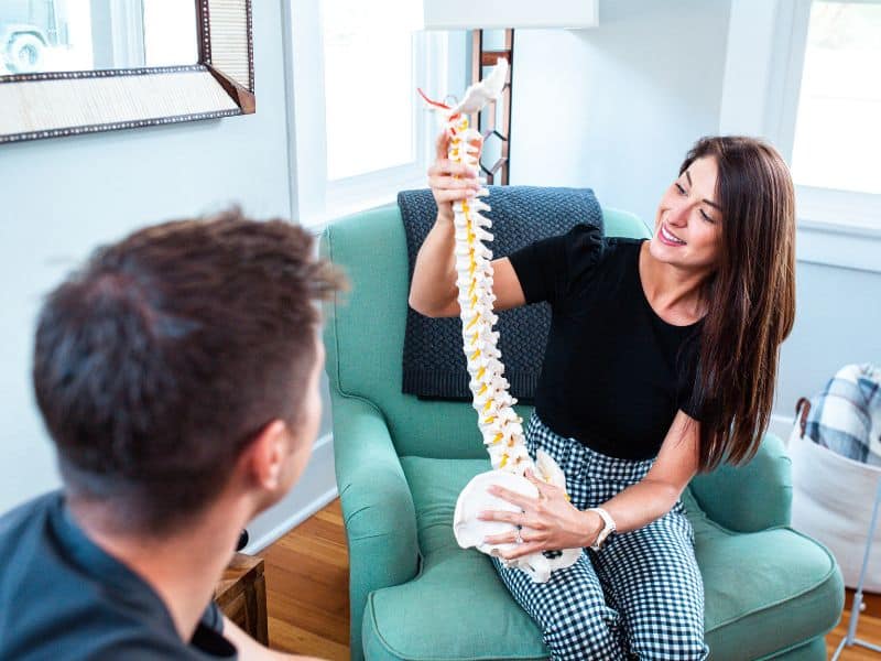 A MovementX provider showing a model of the spine to a patient in a treatment session.